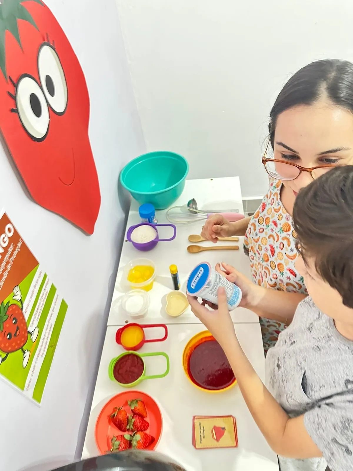 Victória em atendimento com uma criança, com os alimentos na mesa