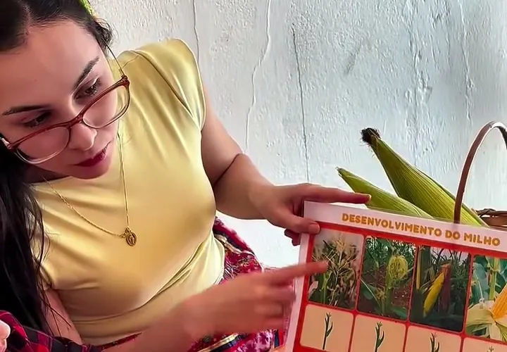 Victória mostrando o desenvolvimento do milho numa oficina com crianças